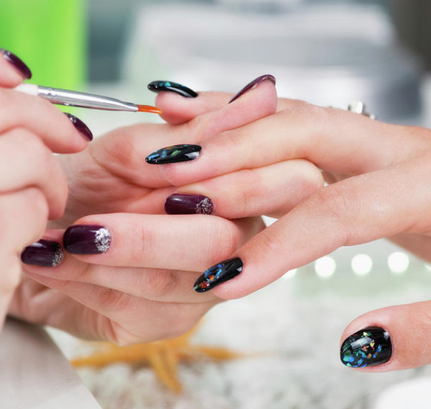 Manicurist applying black with a blue spots polish