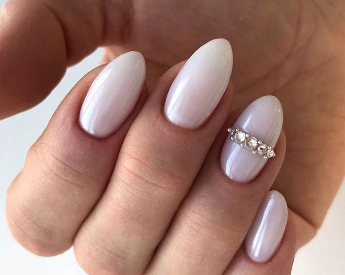 Beautiful finger nails in pink color with a wedding ring