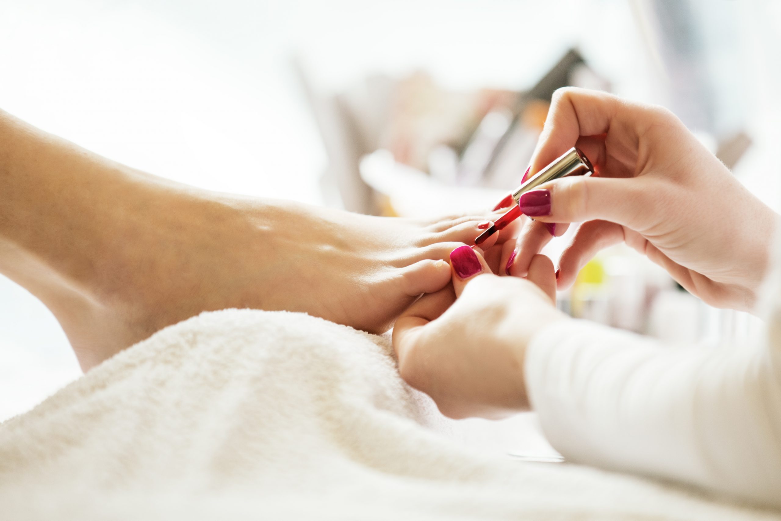 Pedicurist applying toe red nail polish