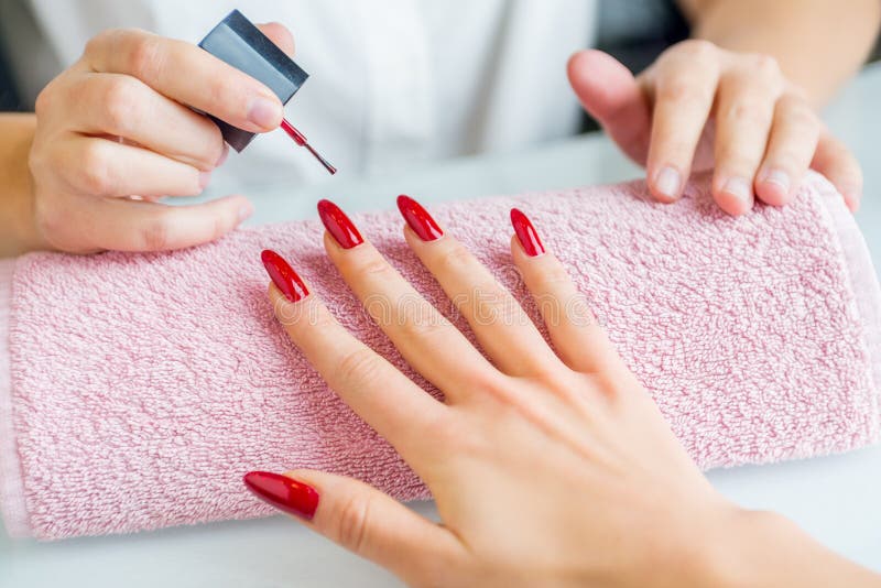 Nail Technician apply two coats of red polish