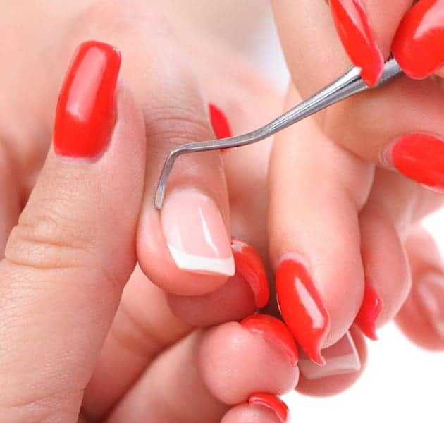 Manicurist scraping a finger cuticle