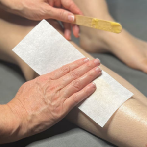 Manicurist applying full leg waxing